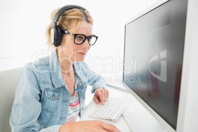 Blonde designer wearing headphones working at computer