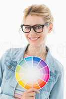 Blonde designer holding colour wheel smiling at camera