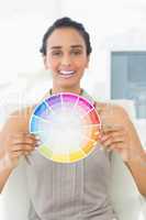 Happy designer at her desk showing colour wheel to camera