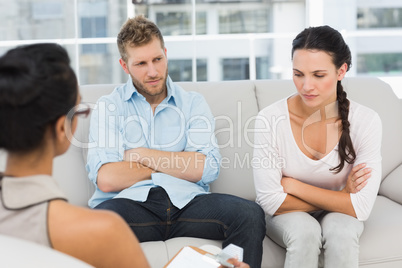 Unhappy couple with arms crossed at therapy session