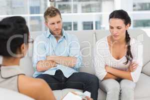 Unhappy couple with arms crossed at therapy session
