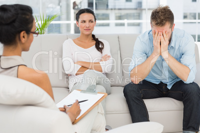 Unhappy couple sitting on sofa at therapy session