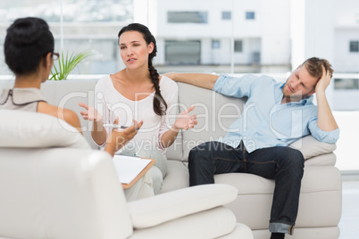 Angry couple sitting on couch talking to therapist