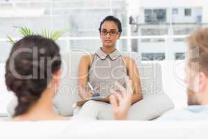 Therapist listening to unhappy couple and taking notes