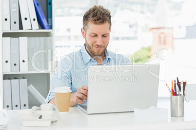 Smiling man working at his desk on laptop