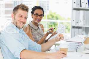 Business partners working together at desk smiling at camera