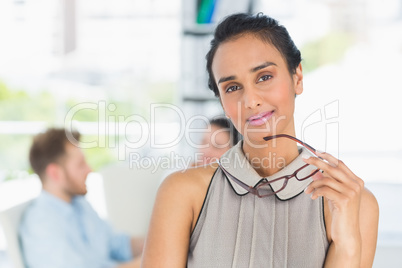 Young woman smiling at camera holding her glasses