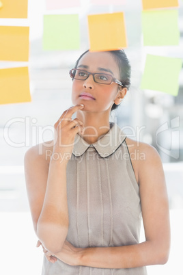 Young designer looking up at sticky notes on window