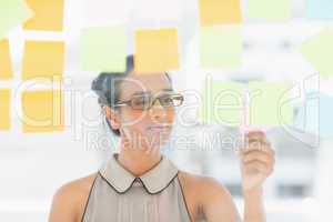 Young designer looking at sticky notes on window