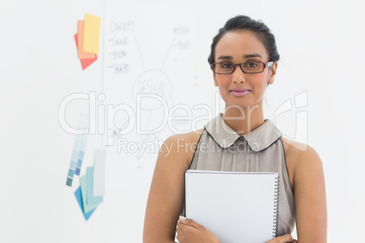 Designer holding notebook and smiling at camera