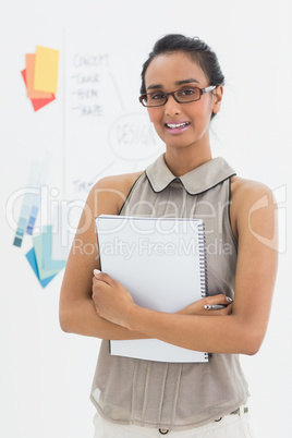 Designer holding notepad and smiling at camera