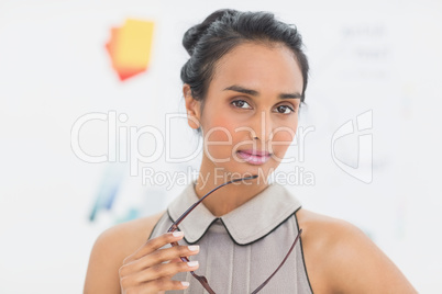 Serious designer looking at camera holding her glasses