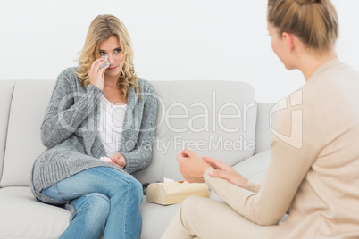 Therapist talking to crying patient on the sofa