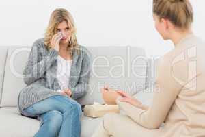 Therapist talking to crying patient on the sofa