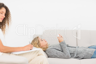 Therapist taking notes on her patient on the couch