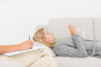 Therapist taking notes on her patient on the sofa