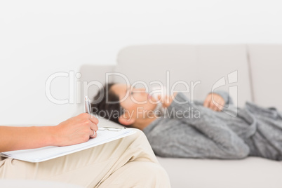 Therapist taking notes on her crying patient on the sofa