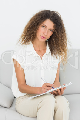 Serious therapist looking at camera taking notes