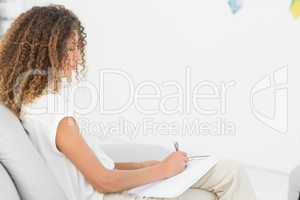 Therapist taking notes on clipboard sitting on couch