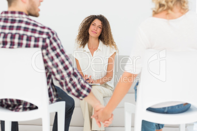 Therapist smiling at reconciled couple holding hands