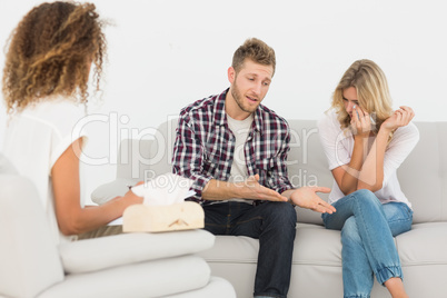 Man speaking to therapist at couples therapy while woman is cryi