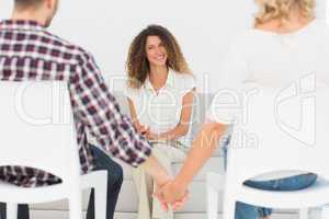 Happy therapist smiling at reconciled couple holding hands