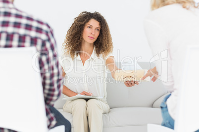 Concerned therapist handing a tissue to woman at couples therapy