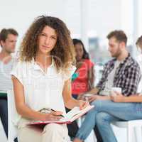 Focused woman writing while colleagues are talking behind her