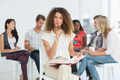 Focused woman looking at camera while colleagues are talking beh
