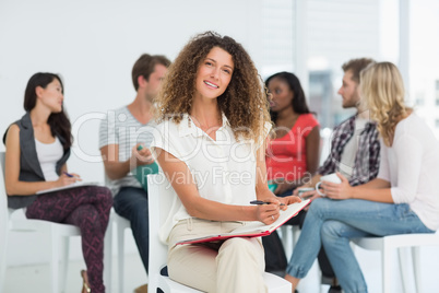 Smiling woman looking at camera while colleagues are talking beh