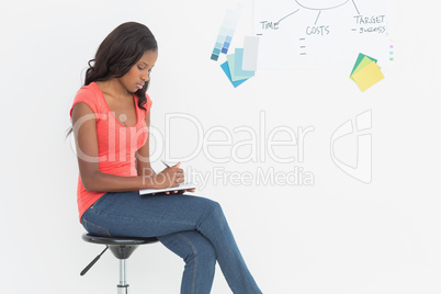Designer sitting and writing in front of whiteboard