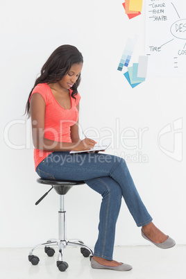 Happy designer sitting and writing in front of whiteboard