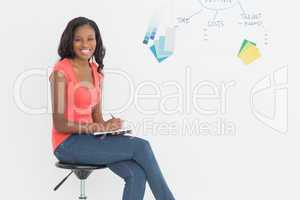 Smiling designer sitting and writing in front of whiteboard