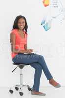 Cheerful designer sitting and writing in front of whiteboard