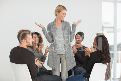 Rehab group applauding happy woman standing up