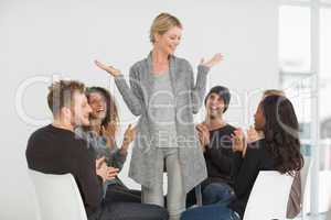 Rehab group applauding happy woman standing up