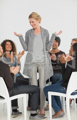 Rehab group applauding smiling woman standing up