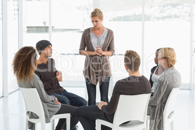 Rehab group listening to woman standing up introducing herself