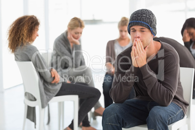 Upset man at rehab group with hands to face