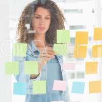 Focused designer looking at sticky notes on window