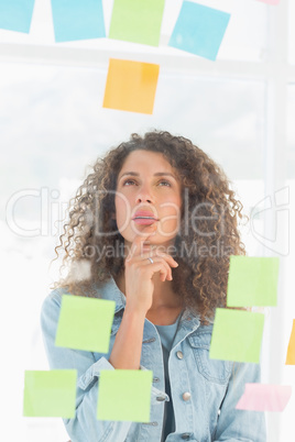 Thinking pretty designer looking at sticky notes on window