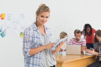 Smiling young designer using her tablet pc in front of her colle