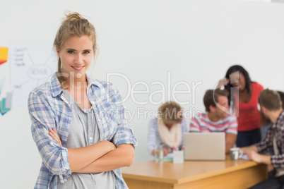 Smiling young designer standing in front of her colleagues