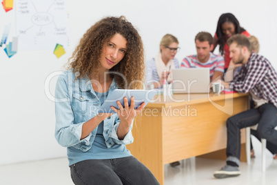 Happy designer sitting in front of her colleagues using digital