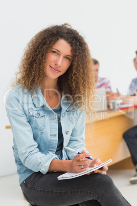 Cheerful designer sitting in front of her colleagues using digit
