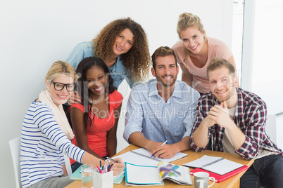 Team of happy young designers having a meeting smiling at camera