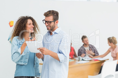 Happy designers looking at digital tablet together and chatting