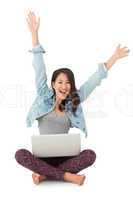 Asian woman cheering at camera with laptop sitting on floor