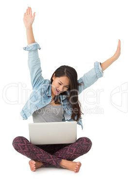 Asian woman cheering with laptop sitting on floor