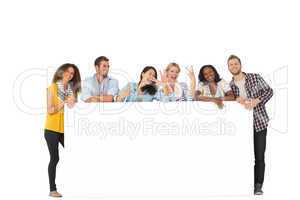 Happy group of young friends leaning on large poster